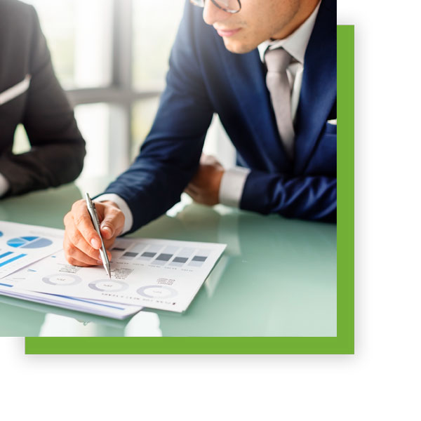 man at a desk showing financials to another person